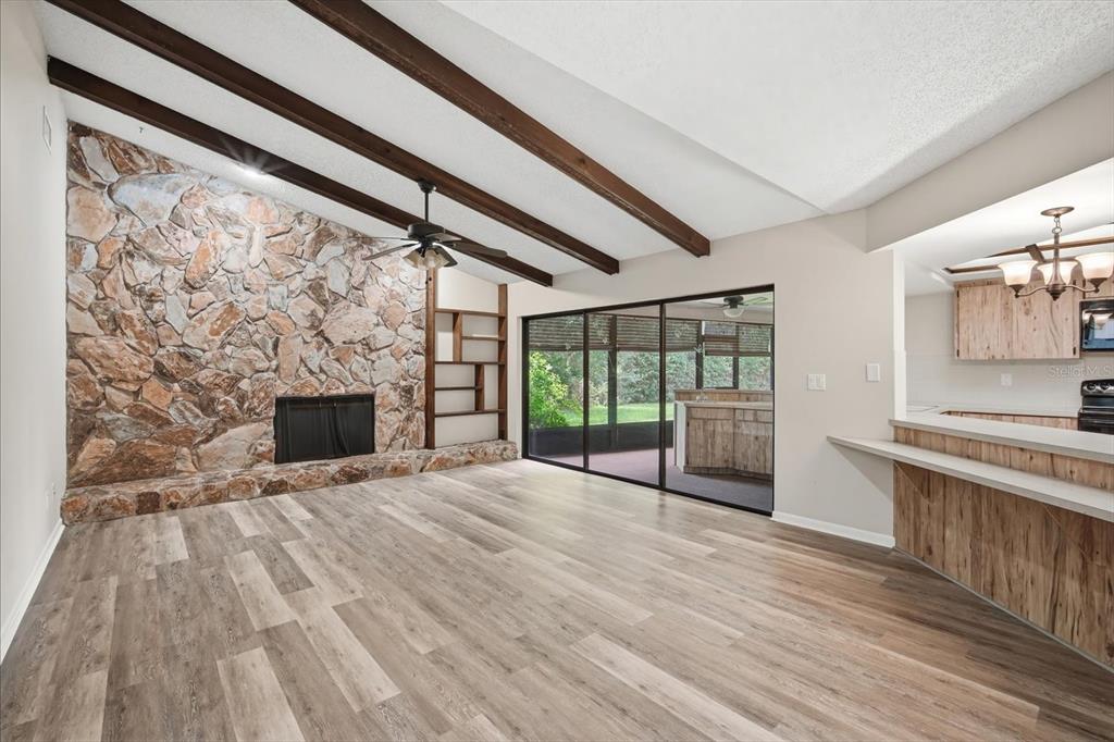A living room features a stone fireplace, wood ceiling beams, and sliding glass patio doors — 1405 LAUREL COURT, PLANT CITY, FL