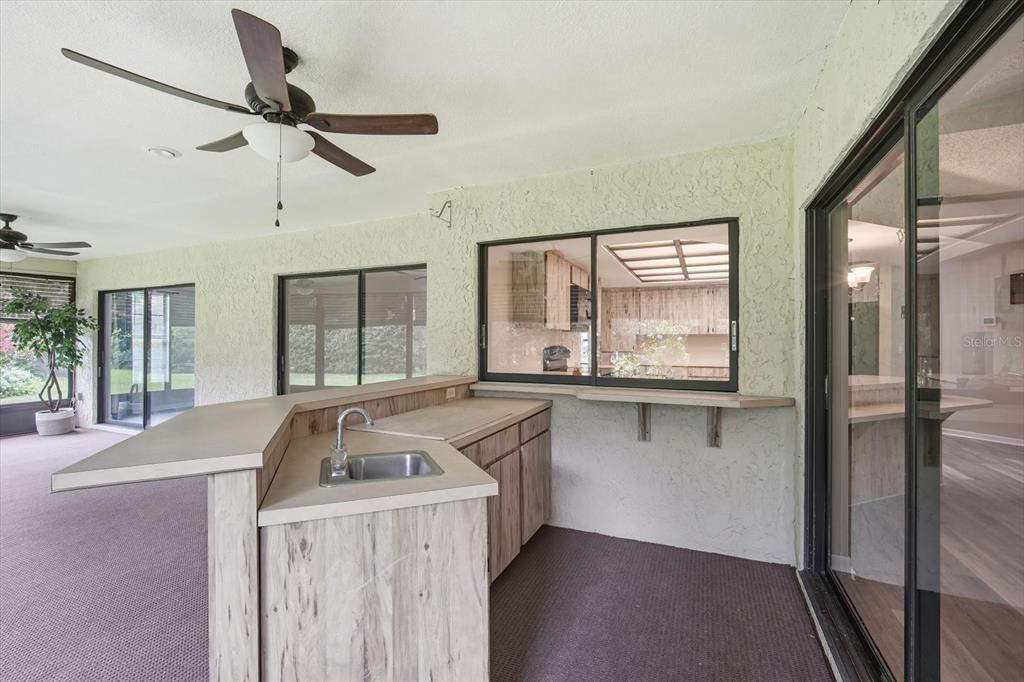 A covered patio features a wet bar with a sink, wood-look cabinets, and sliding doors — 1405 LAUREL COURT, PLANT CITY, FL