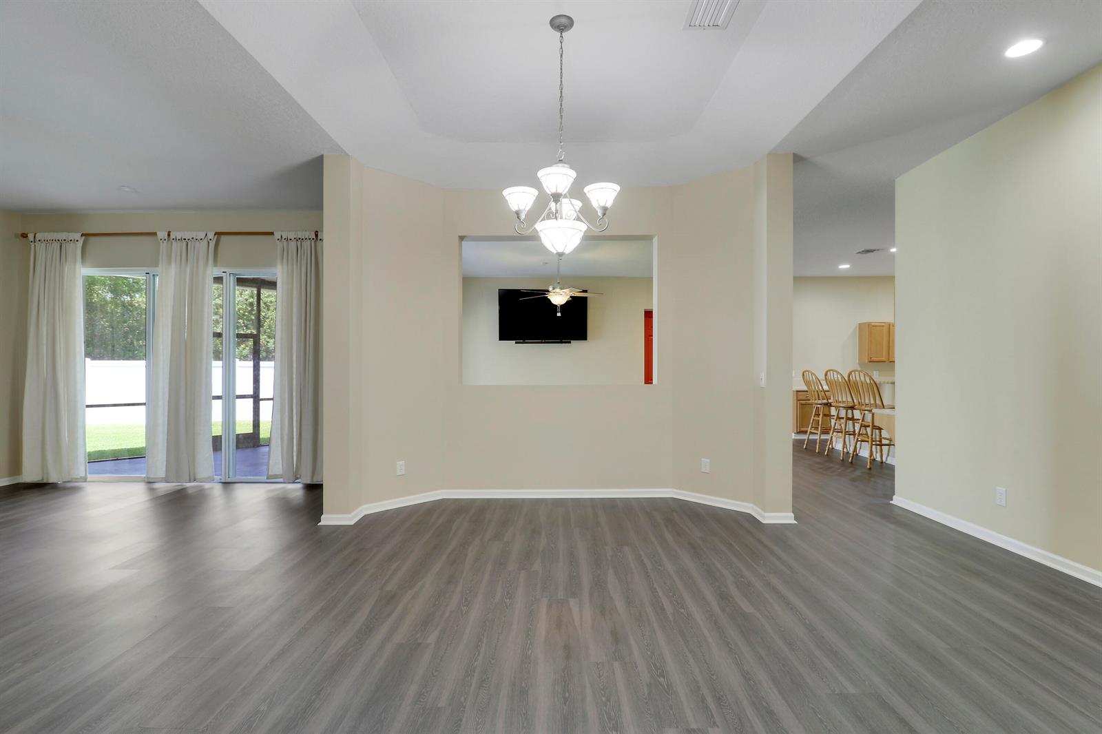 An empty dining area features a tray ceiling, a chandelier, and wood-look flooring — 10075 Freesian Way, Lake Worth FL 33449, LAKE WORTH, FL
