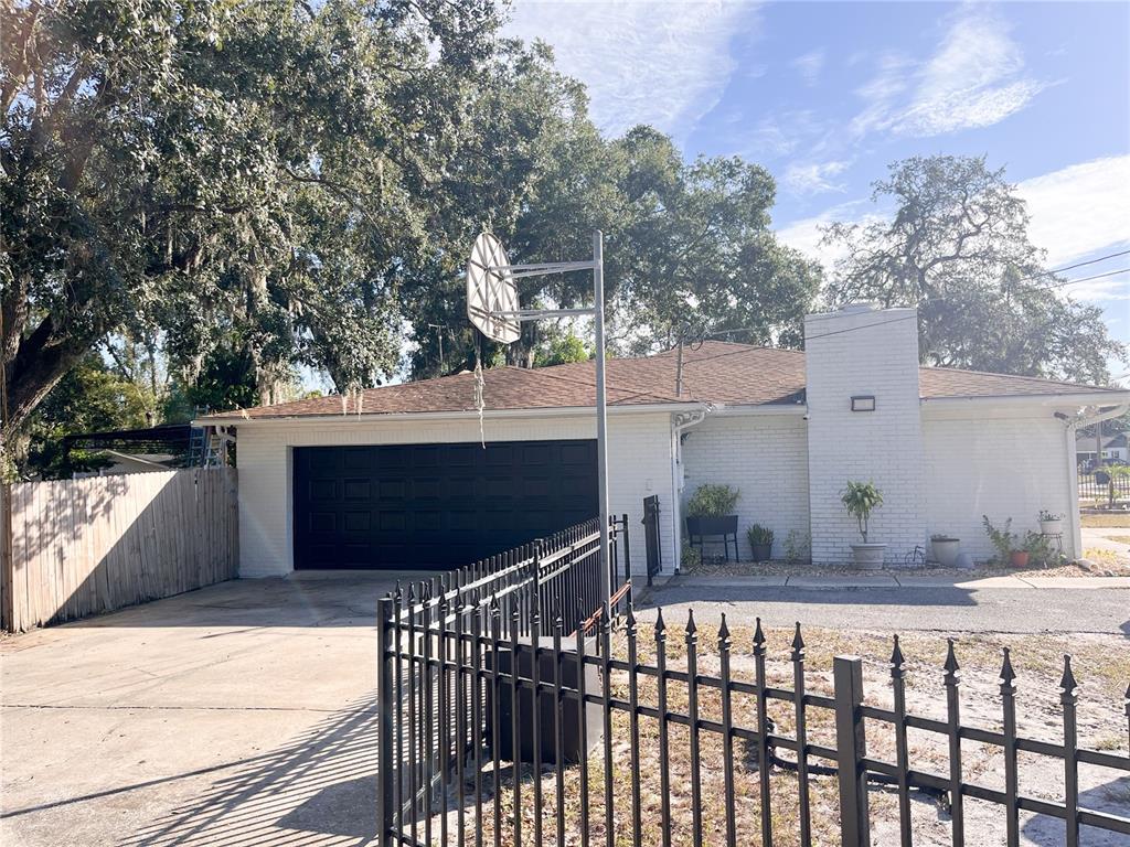 The exterior of a white concrete block house features a covered patio and yard — 1802 E KNOLLWOOD STREET, TAMPA, FL