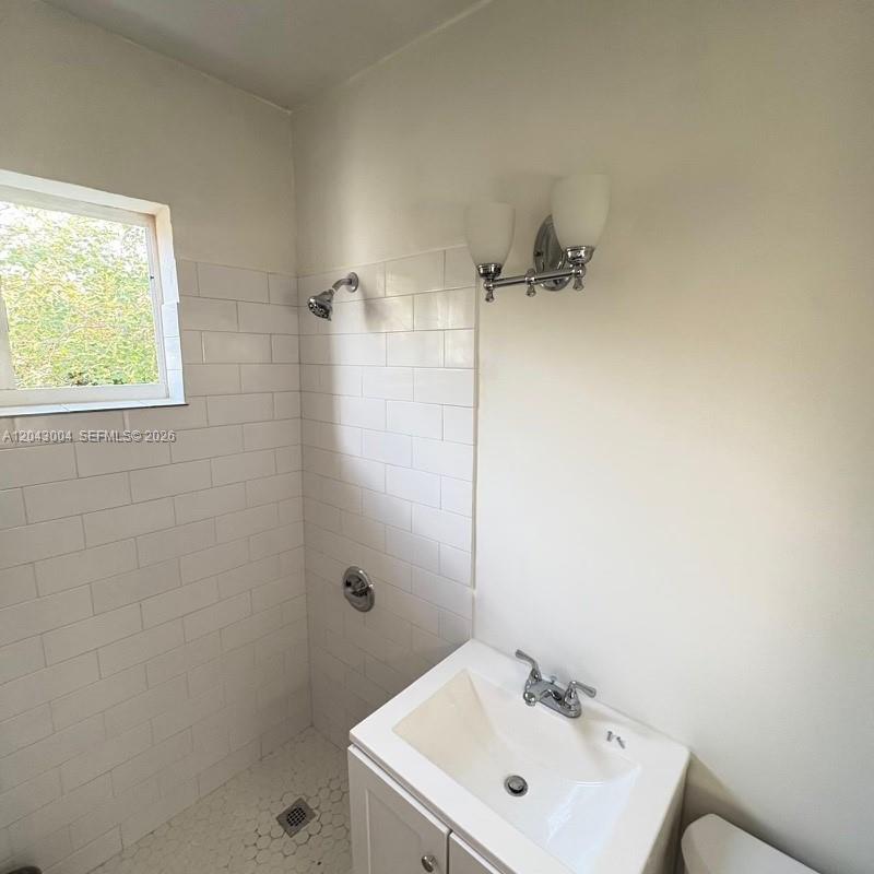 A bathroom features a white subway-tiled shower, a pedestal sink, and a wall-mounted light fixture — 1000 Biarritz Dr # 3, Miami Beach FL 33141, MIAMI BEACH, FL