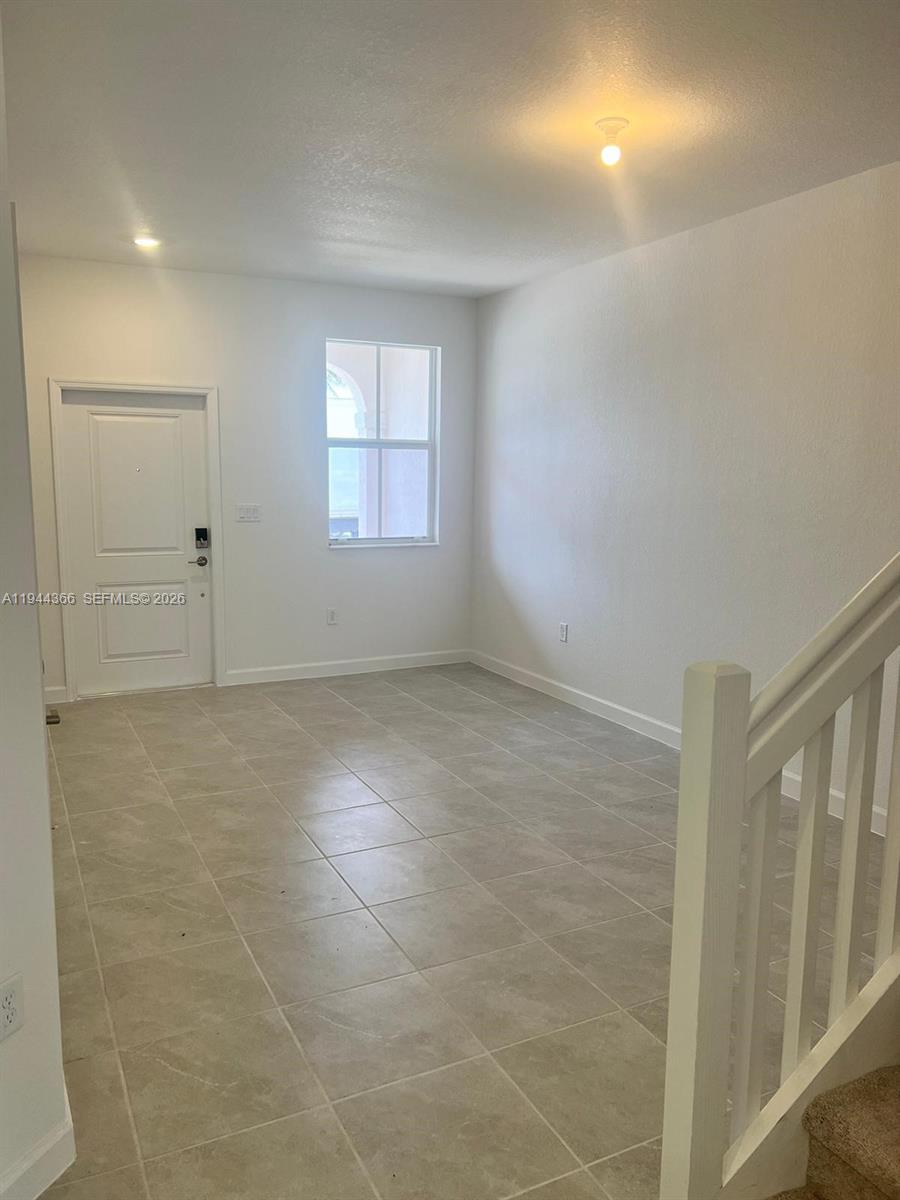 This room features light-colored tile flooring, white walls, a single window, and a staircase — 12560 NW 22nd Pl, Miami FL 33167, MIAMI, FL