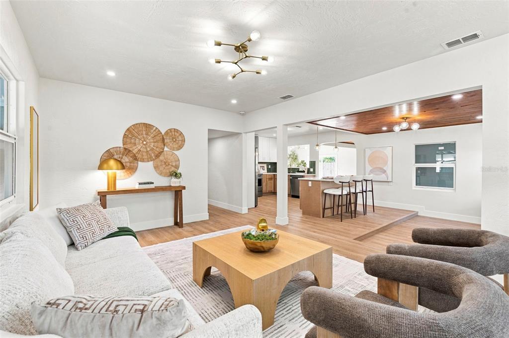 A living room with light wood floors, a wooden coffee table, and an adjacent kitchen — 7326 11TH AVENUE N, ST PETERSBURG, FL