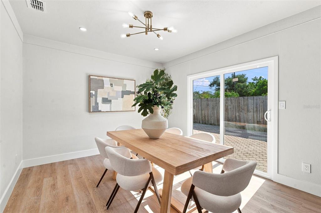 A dining room features a wooden table, six chairs, a modern chandelier, and sliding glass doors — 7326 11TH AVENUE N, ST PETERSBURG, FL