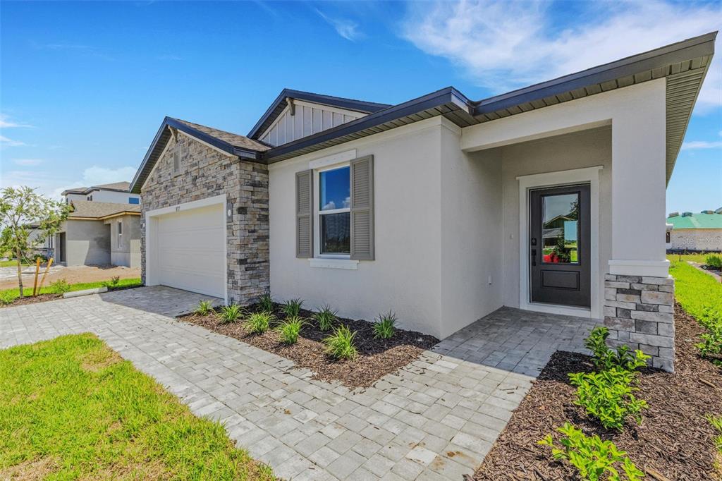 A single-story house exterior features a stone-accented garage, a paved walkway, and a covered entryway — 8717 CANARD CV, PALMETTO, FL