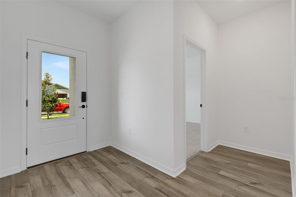 An entryway with wood-look flooring, a white front door with a window, and an interior doorway — 8717 CANARD CV, PALMETTO, FL