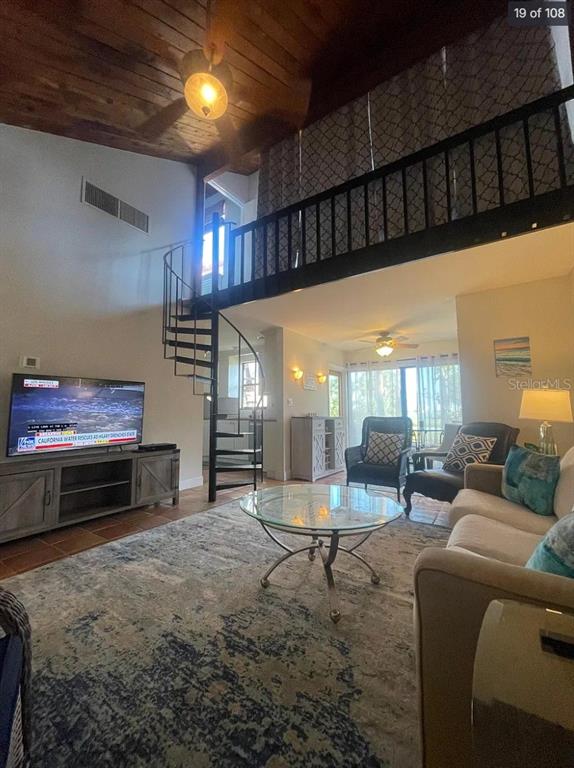 A living room features a spiral staircase, a loft area, and a vaulted wood ceiling — 109 PASS KEY ROAD UNIT 109, SARASOTA, FL