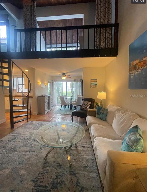 A living room with a spiral staircase, a loft, and a glass coffee table — 109 PASS KEY ROAD UNIT 109, SARASOTA, FL