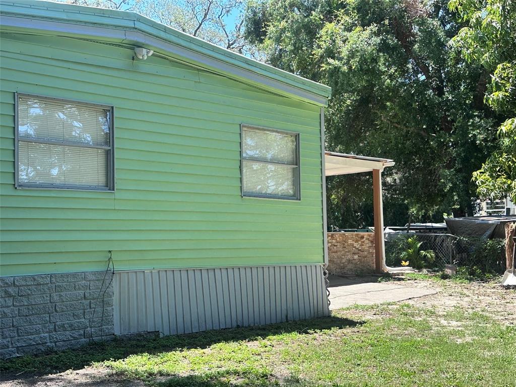 The exterior of a light green mobile home features horizontal siding and a stone-patterned skirt — 6606 CORBIN LANE, NEW PORT RICHEY, FL