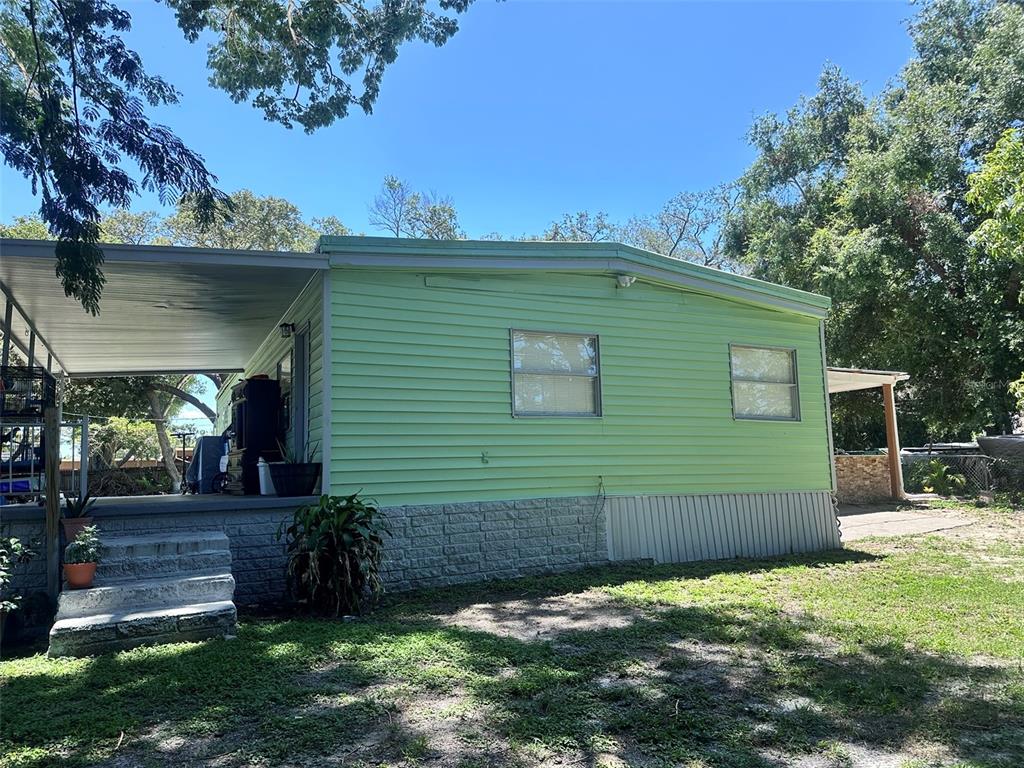 A light green mobile home with a covered porch and concrete steps sits on a lot — 6606 CORBIN LANE, NEW PORT RICHEY, FL