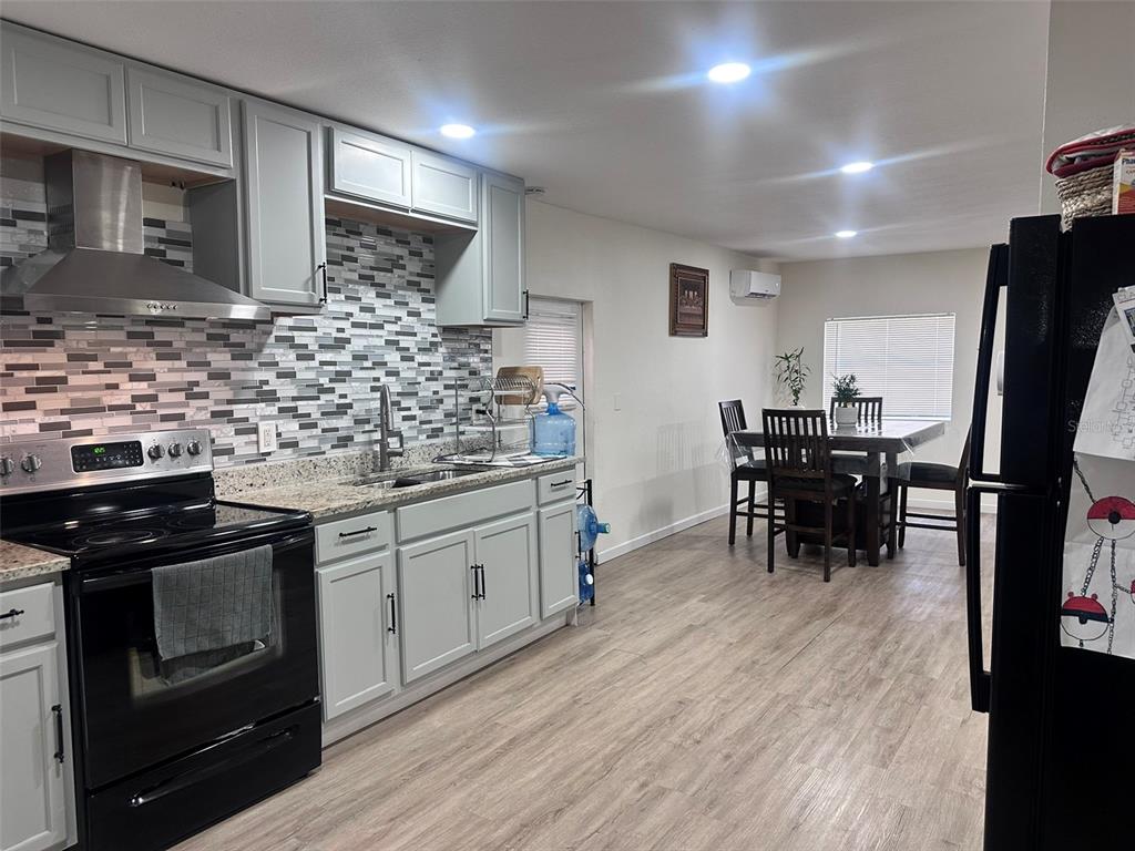 A kitchen with light gray cabinets, a mosaic tile backsplash, and an adjacent dining area — 6606 CORBIN LANE, NEW PORT RICHEY, FL