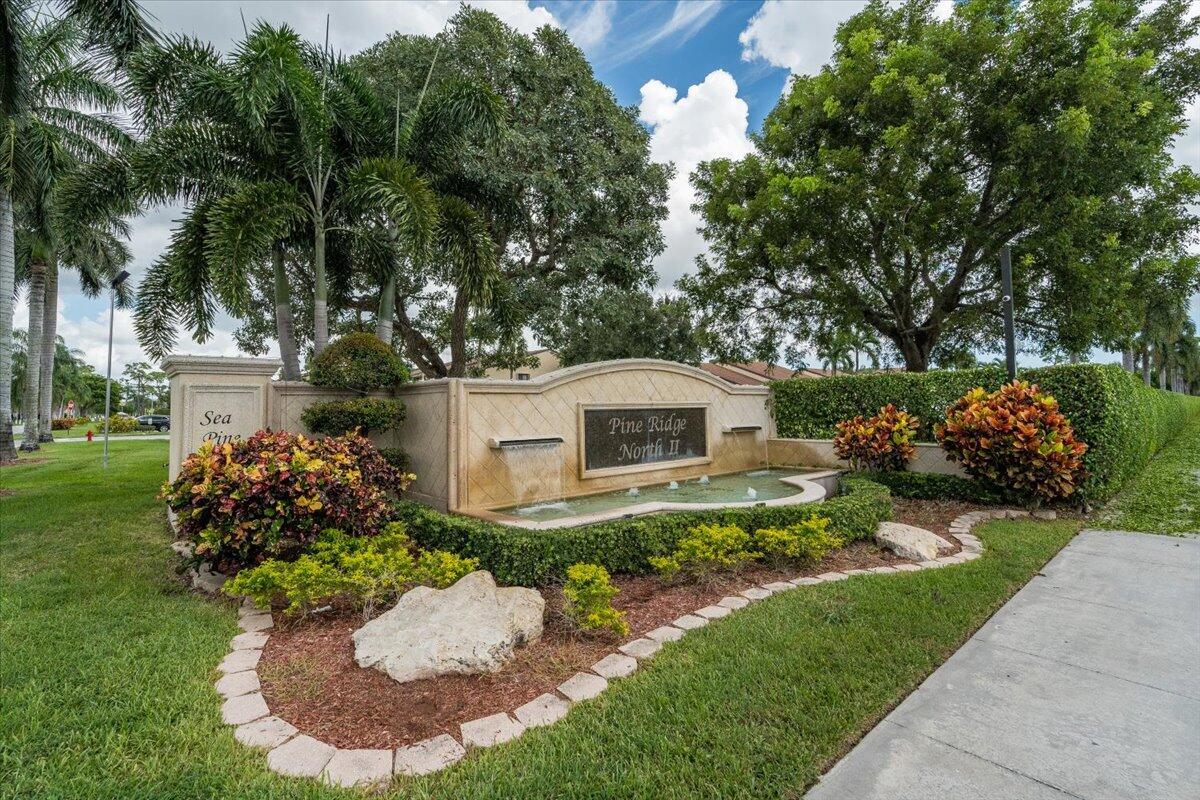 A stone monument sign with a water feature stands in front of landscaped greenery — 630 Sea Pine Way # A, FL 33415, FL