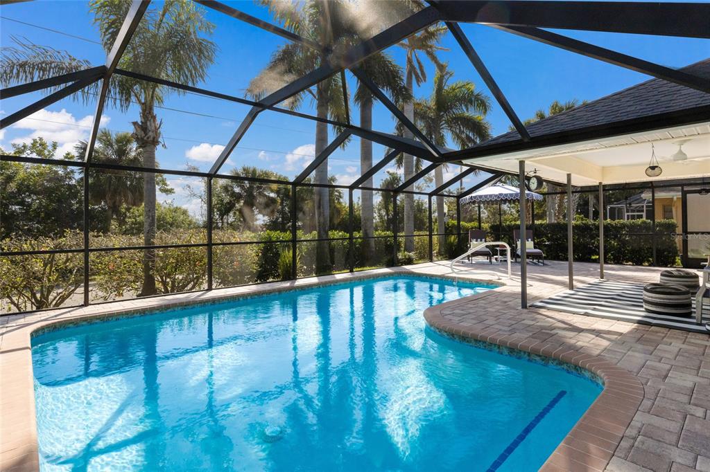 A screened-in patio features a swimming pool, lounge chairs, and a paved deck area — 5107 86TH STREET COURT W, BRADENTON, FL
