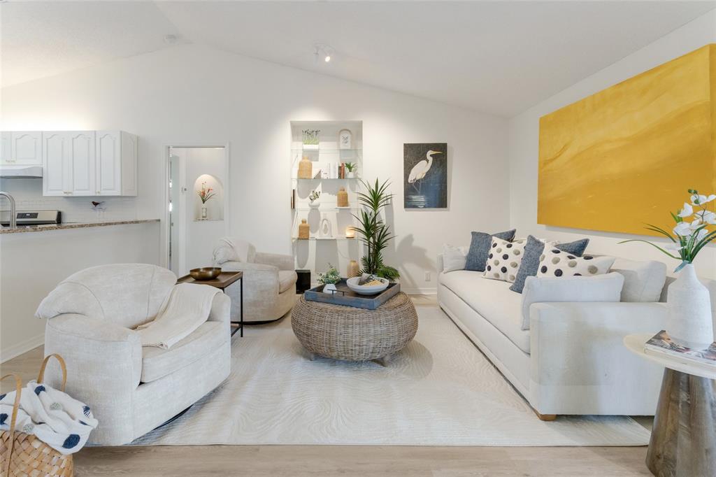 A bright living room features light wood flooring, white furniture, and a view of a pool — 5107 86TH STREET COURT W, BRADENTON, FL