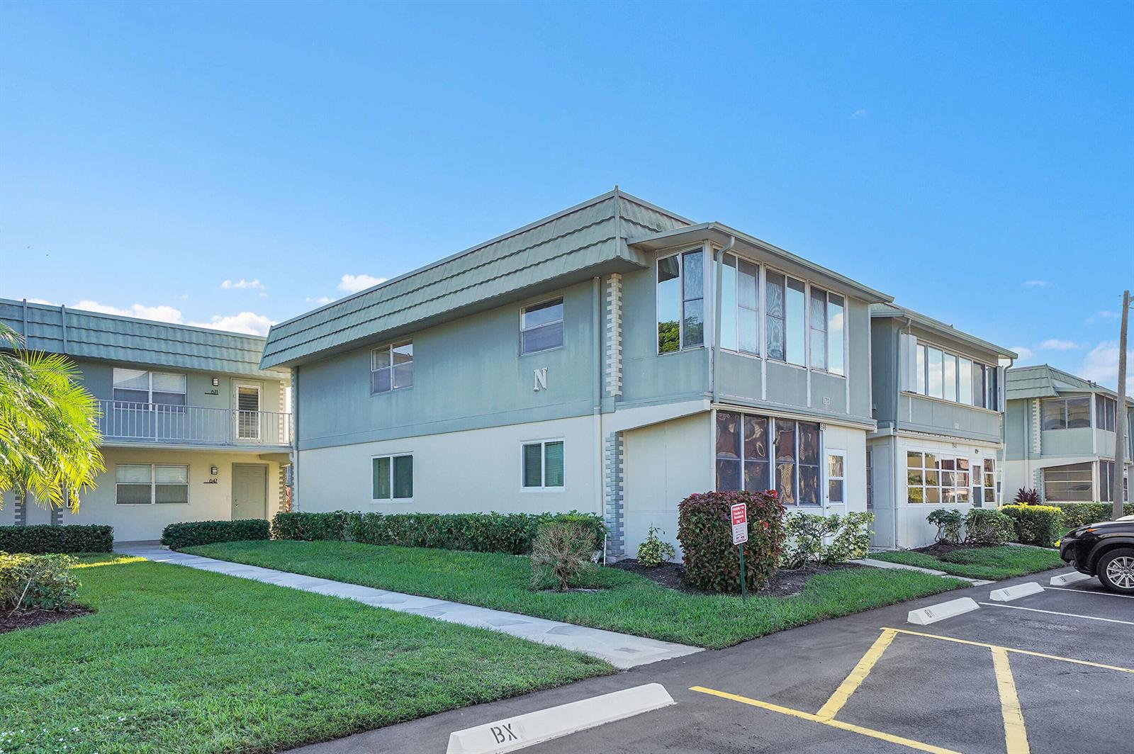 A two-story apartment building with light green siding and a parking lot in the foreground — 646 Flanders N, Delray Beach FL 33484, DELRAY BEACH, FL
