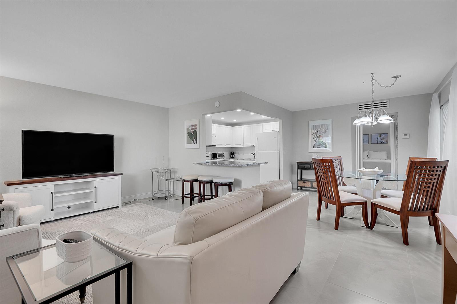 A living room and dining area with white tile floors, a kitchen bar, and furniture — 646 Flanders N, Delray Beach FL 33484, DELRAY BEACH, FL