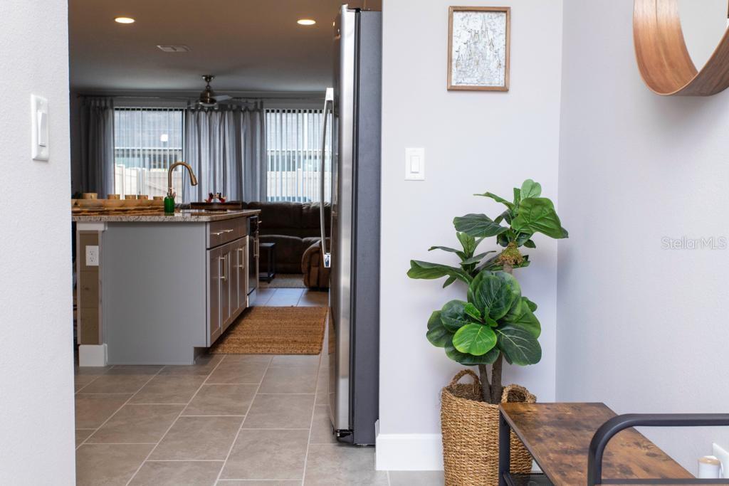 A view from a hallway looking into a kitchen with gray cabinets and tile flooring — 4711 TERRA ESMERALDA DRIVE, KISSIMMEE, FL