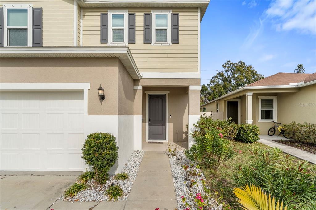 A two-story house exterior features a beige facade, a garage, and a front entryway — 7710 SUNSHINE BRIDGE AVE, GIBSONTON, FL