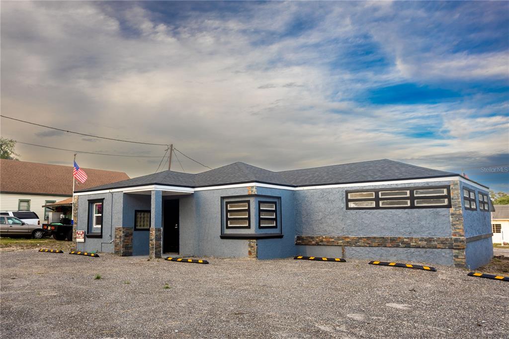 A single-story blue commercial building with a gravel parking lot and stone accents — 115 N 10TH STREET, HAINES CITY, FL