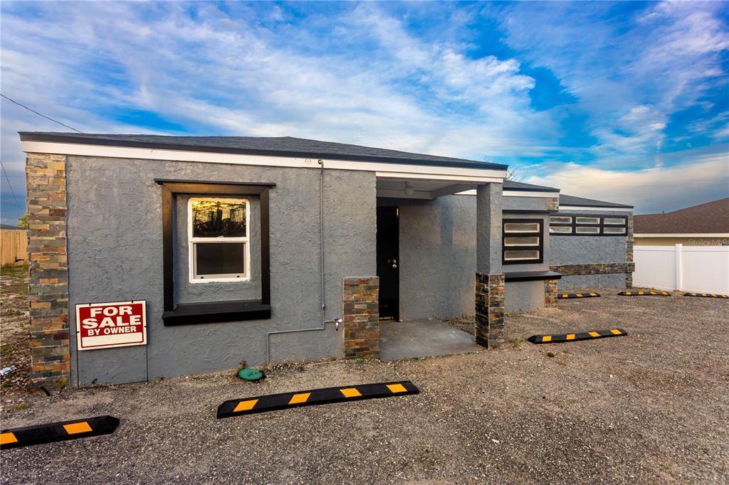 A gray stucco building with stone accents and a gravel parking area in front — 115 N 10TH STREET, HAINES CITY, FL