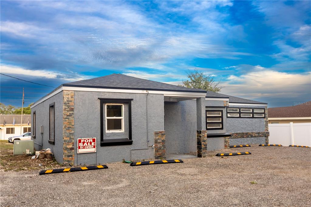 A gray stucco commercial building with stone accents and a gravel parking lot — 115 N 10TH STREET, HAINES CITY, FL