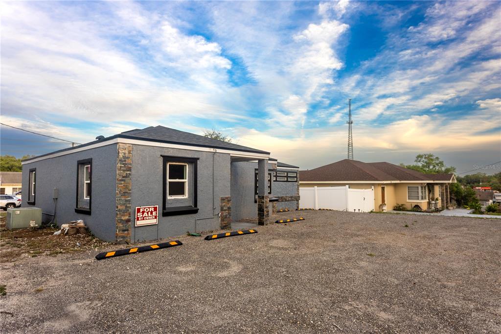 A gray stucco building with stone accents sits on a gravel lot with parking bumpers — 115 N 10TH STREET, HAINES CITY, FL