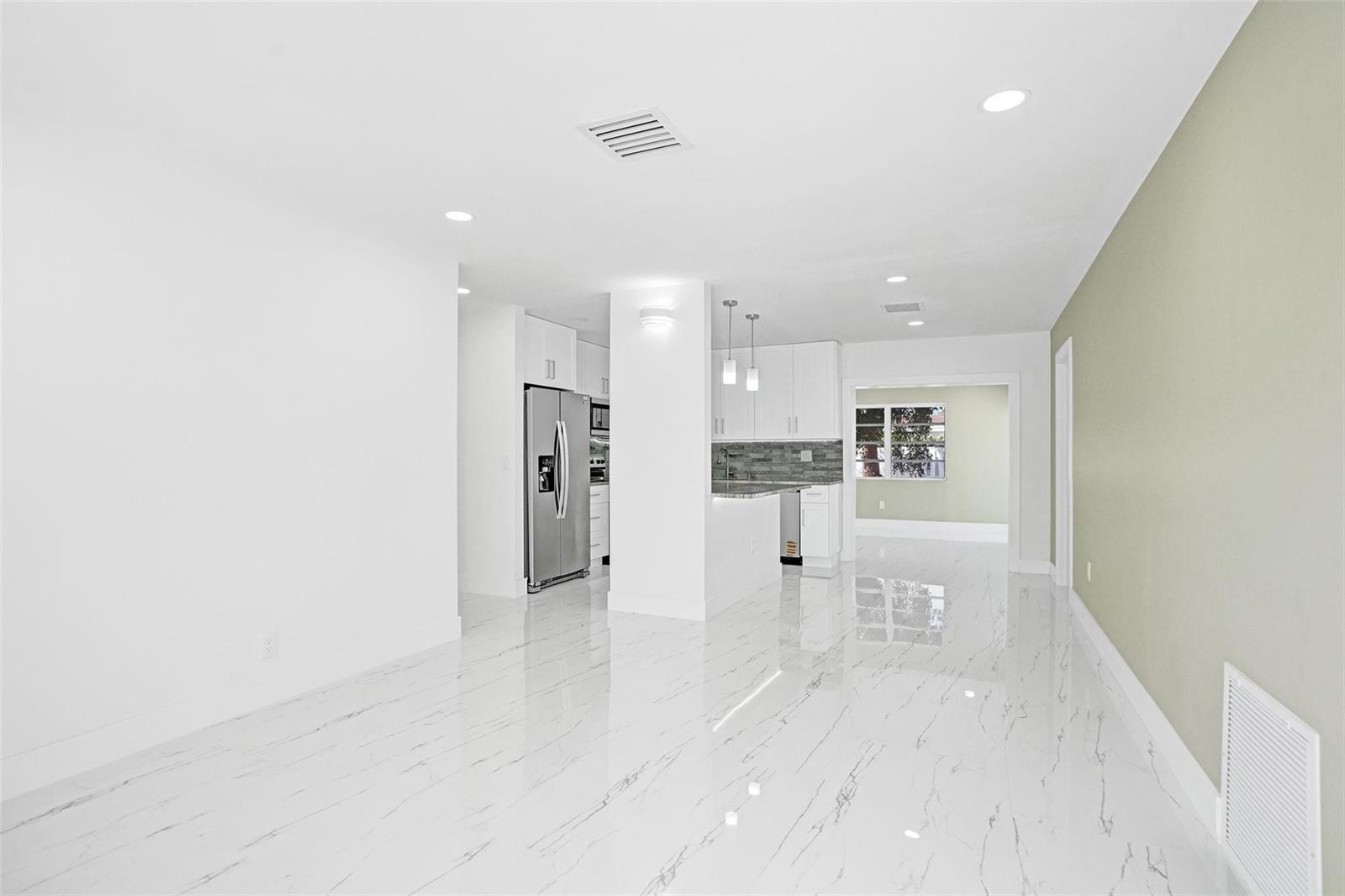 An open-concept room features white marble-look tile flooring, white cabinetry, and a light green wall — 1437 SW 1st Avenue, Deerfield Beach FL 33441, DEERFIELD BEACH, FL