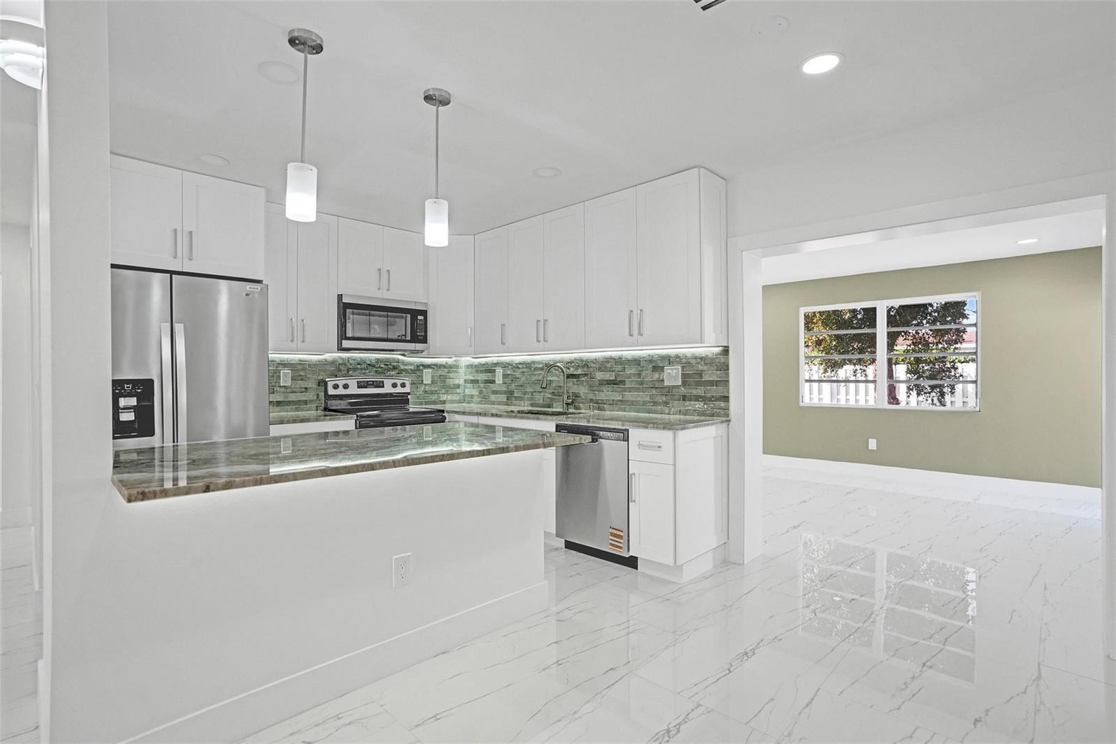 A modern kitchen features white cabinets, stainless steel appliances, and a marble-patterned tile floor — 1437 SW 1st Avenue, Deerfield Beach FL 33441, DEERFIELD BEACH, FL