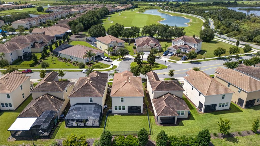 An aerial view shows a suburban neighborhood with houses, a golf course, and a pond — 8813 BETH PAGE LANE, DAVENPORT, FL