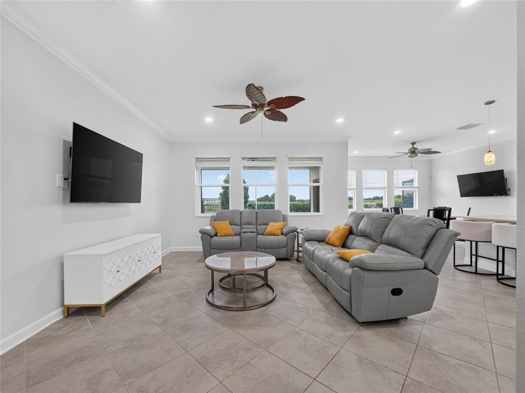 A living room features gray leather sofas, a white media console, and tile flooring — 8813 BETH PAGE LANE, DAVENPORT, FL