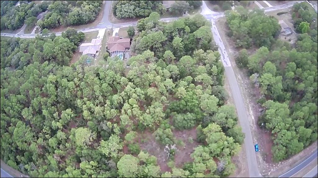 An aerial view shows houses nestled among dense trees in a suburban neighborhood — 9223 N BERTIN DRIVE, CITRUS SPRINGS, FL