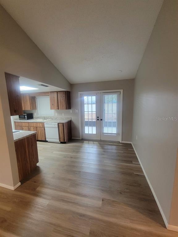 A kitchen with wood cabinets and light flooring opens to a dining area with doors — 1305 CALAMONDIN DRIVE, HOLIDAY, FL