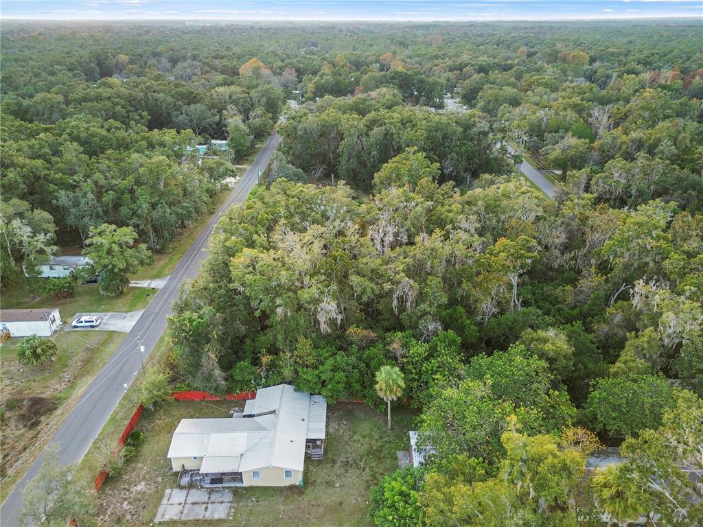 An aerial view shows a house with a metal roof surrounded by dense forest — 6301 W GOLDENLEAF LANE, CRYSTAL RIVER, FL