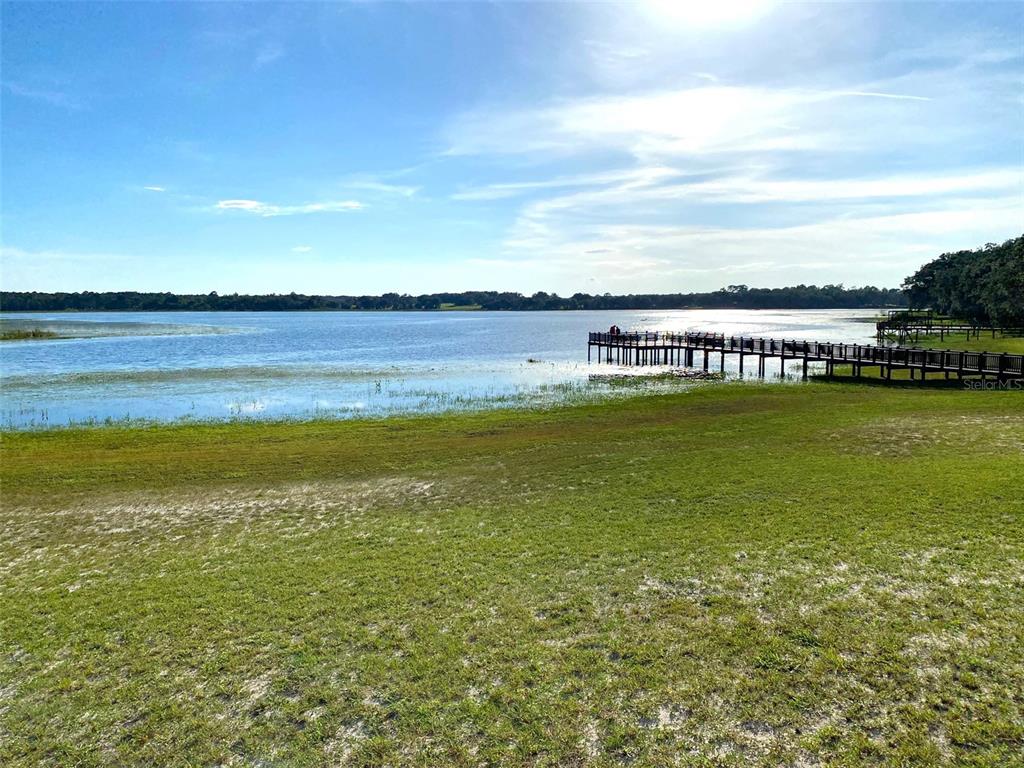 A wooden pier extends into a large lake from a grassy, sunlit shoreline — Lots 11.12 SW SHOREWOOD DRIVE, DUNNELLON, FL