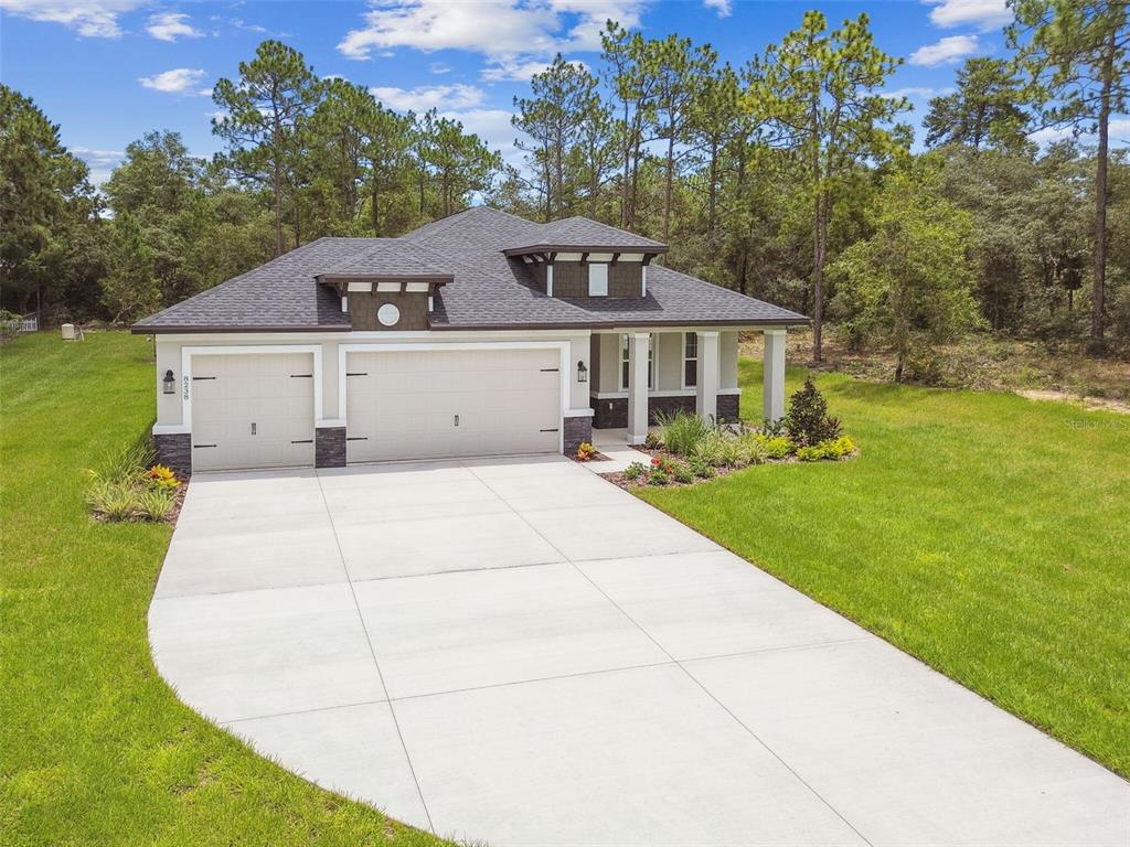 A single-story house with a three-car garage and a concrete driveway sits on a lawn — 11347 STRIPED BASS COURT, NEW PORT RICHEY, FL