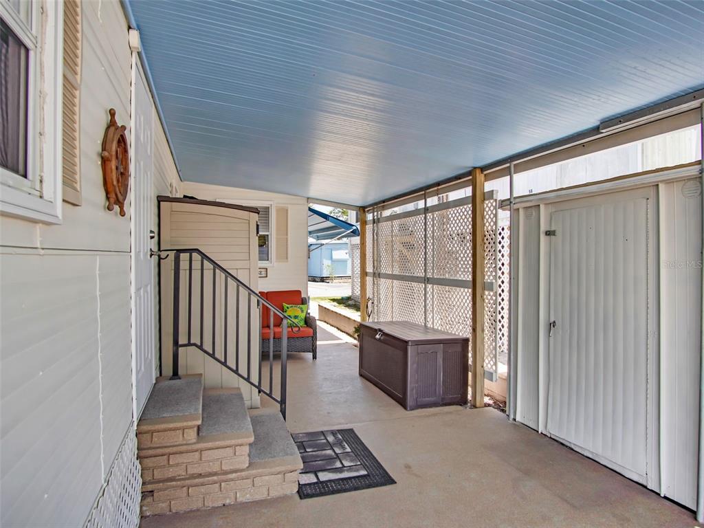 A covered concrete patio features a small staircase, a storage chest, and lattice privacy screens — 800 CHESAPEAKE DRIVE UNIT 55, TARPON SPRINGS, FL
