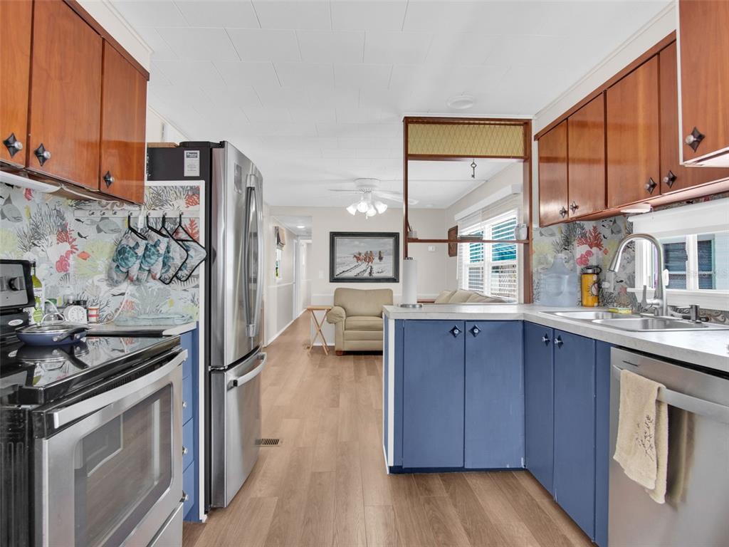 A kitchen features blue lower cabinets, wood upper cabinets, stainless steel appliances, and patterned backsplash — 800 CHESAPEAKE DRIVE UNIT 55, TARPON SPRINGS, FL