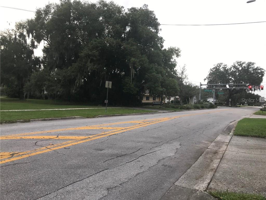 A paved road leads toward a traffic light intersection surrounded by large, mature trees — 315 N SINCLAIR AVENUE, TAVARES, FL