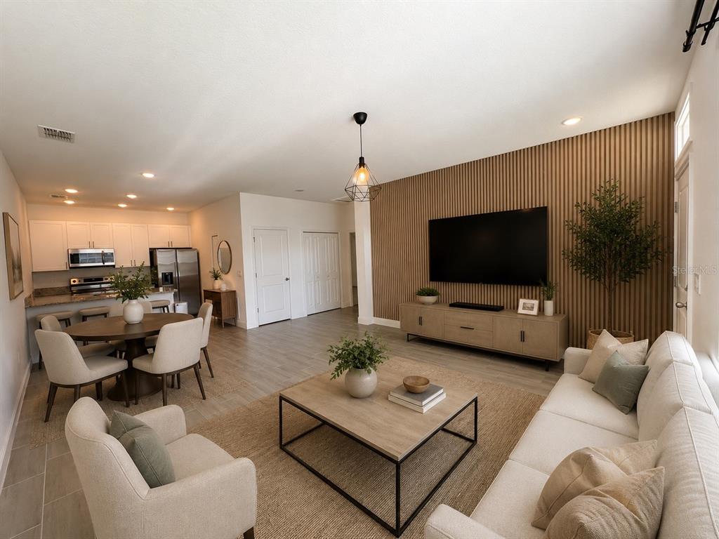 An open-concept living room and kitchen featuring a wood-slatted accent wall and neutral furniture — 1552 CUMIN DRIVE, POINCIANA, FL