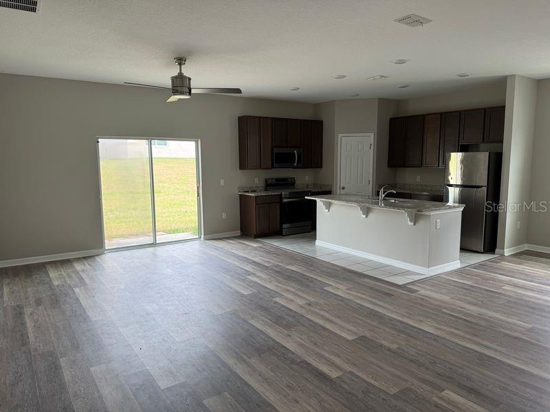 An open-concept kitchen with dark cabinets and a breakfast bar overlooks a living area — 3345 CURLEW AVENUE, LEESBURG, FL