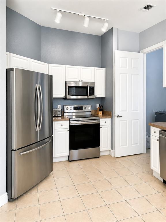 A kitchen features stainless steel appliances, white cabinets, and light-colored tile flooring — 322 TERRACE RIDGE CIRCLE UNIT 322, DAVENPORT, FL