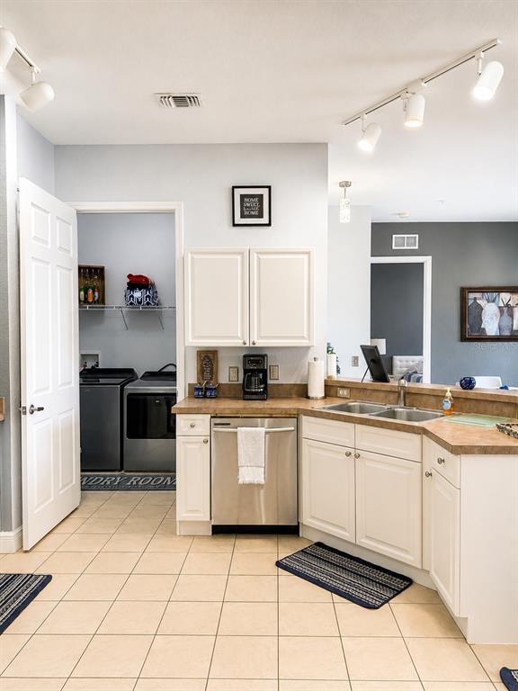 A kitchen with white cabinets, stainless steel appliances, and tile flooring, adjacent to a laundry room — 322 TERRACE RIDGE CIRCLE UNIT 322, DAVENPORT, FL