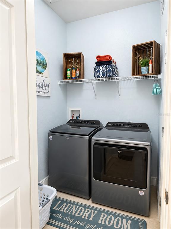 A laundry room features a gray washer and dryer set beneath a wire storage shelf — 322 TERRACE RIDGE CIRCLE UNIT 322, DAVENPORT, FL