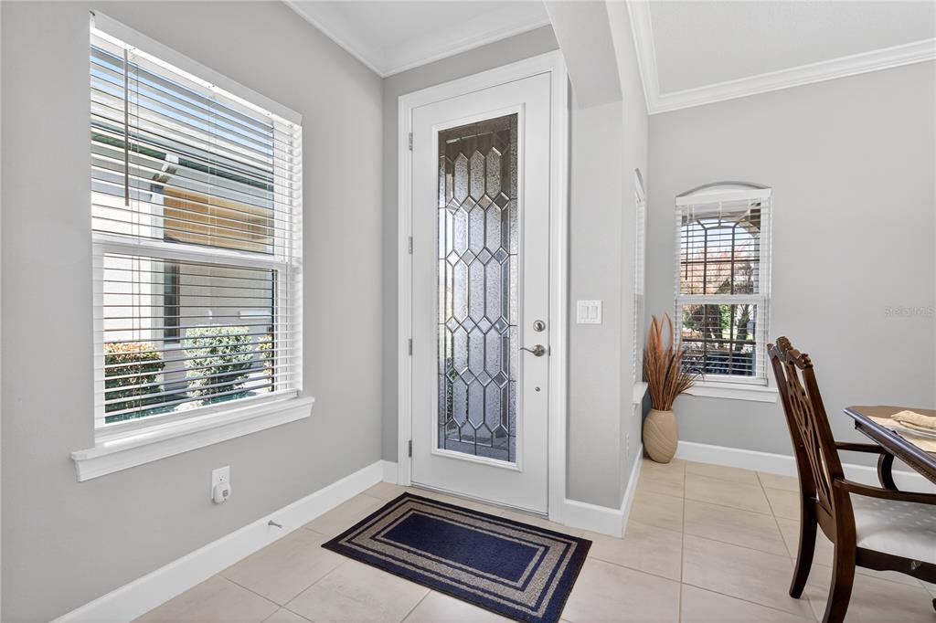 A bright entryway features a white front door with decorative glass, tile floors, and windows — 1282 ZEEK RIDGE STREET, CLERMONT, FL