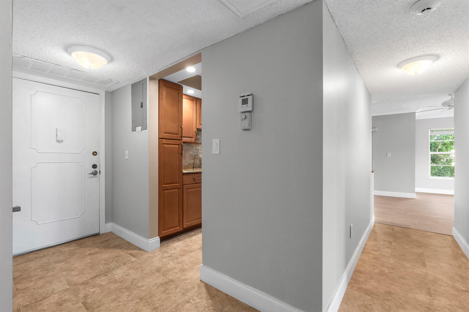 An entryway with tile flooring leads to a kitchen with wood cabinets and a hallway — 950 Ponce De Leon # 3120, Boca Raton FL 33432, BOCA RATON, FL