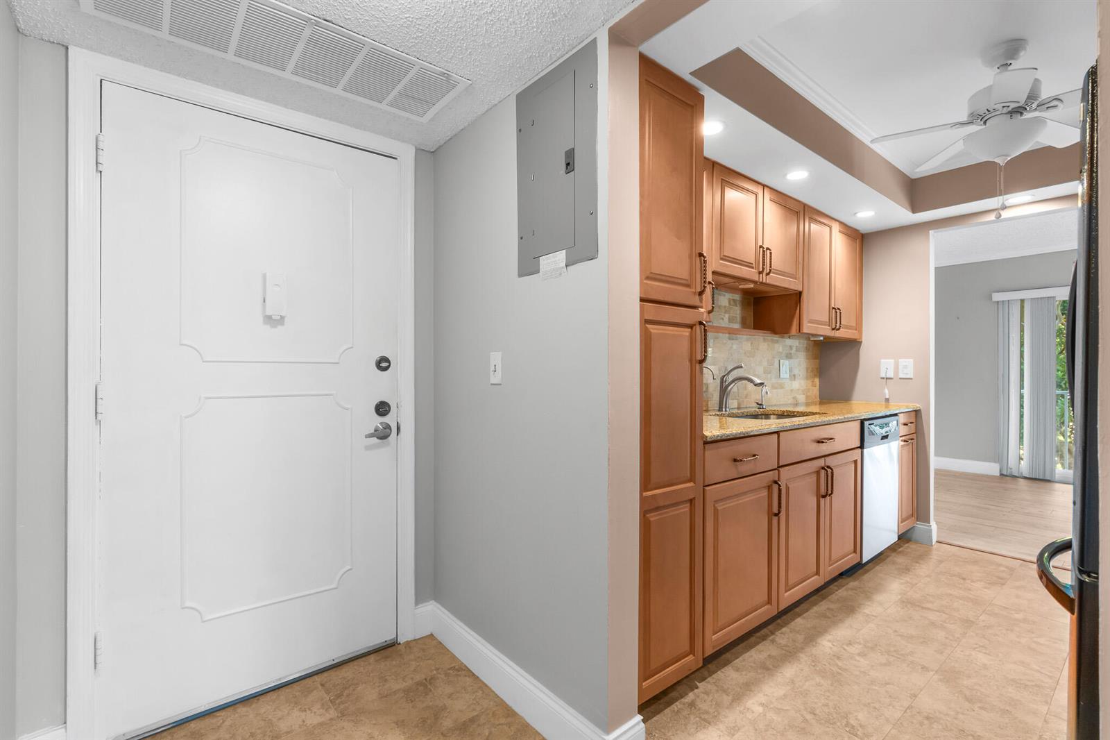 A view of an entryway with a white door next to a small kitchen area — 950 Ponce De Leon # 3120, Boca Raton FL 33432, BOCA RATON, FL