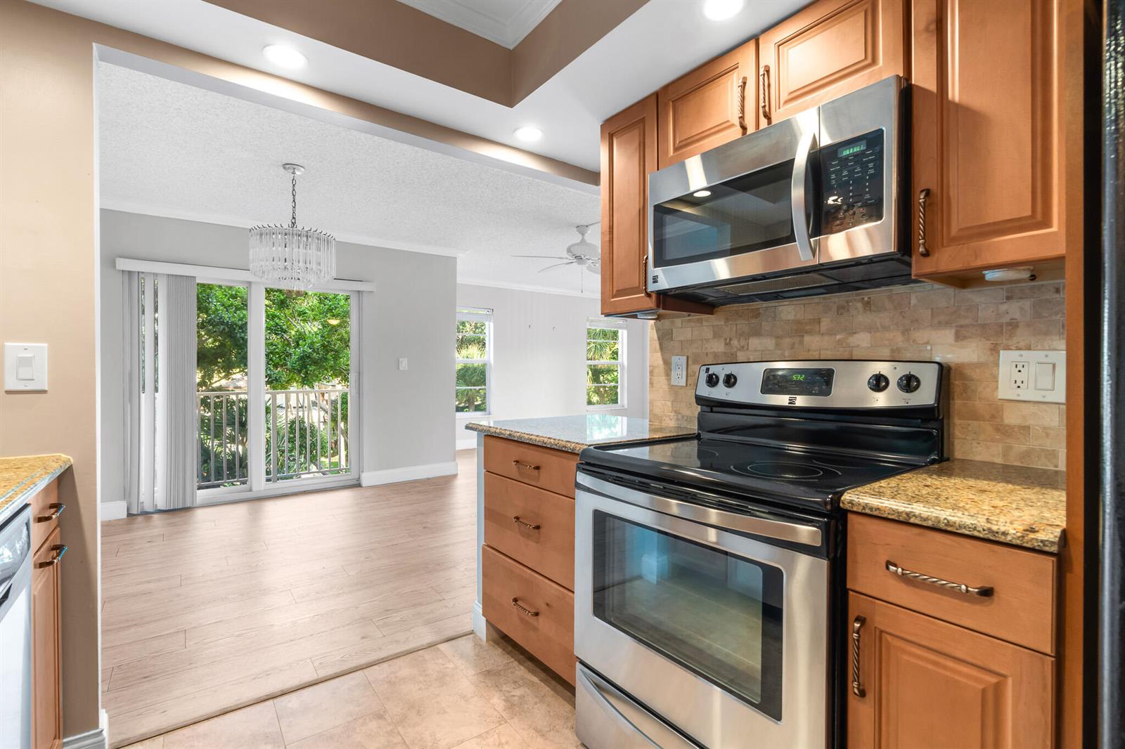 A kitchen with wood cabinets and stainless steel appliances overlooks an open living area — 950 Ponce De Leon # 3120, Boca Raton FL 33432, BOCA RATON, FL