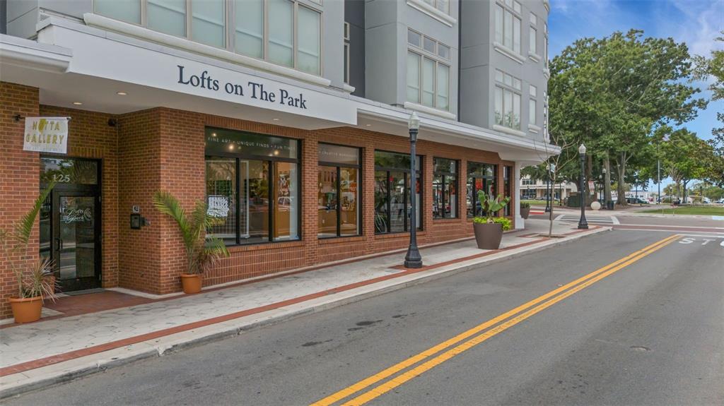 The exterior of a brick building with storefront windows and a sign reading Lofts on The Park — 125 N KENTUCKY AVENUE UNIT 303, LAKELAND, FL