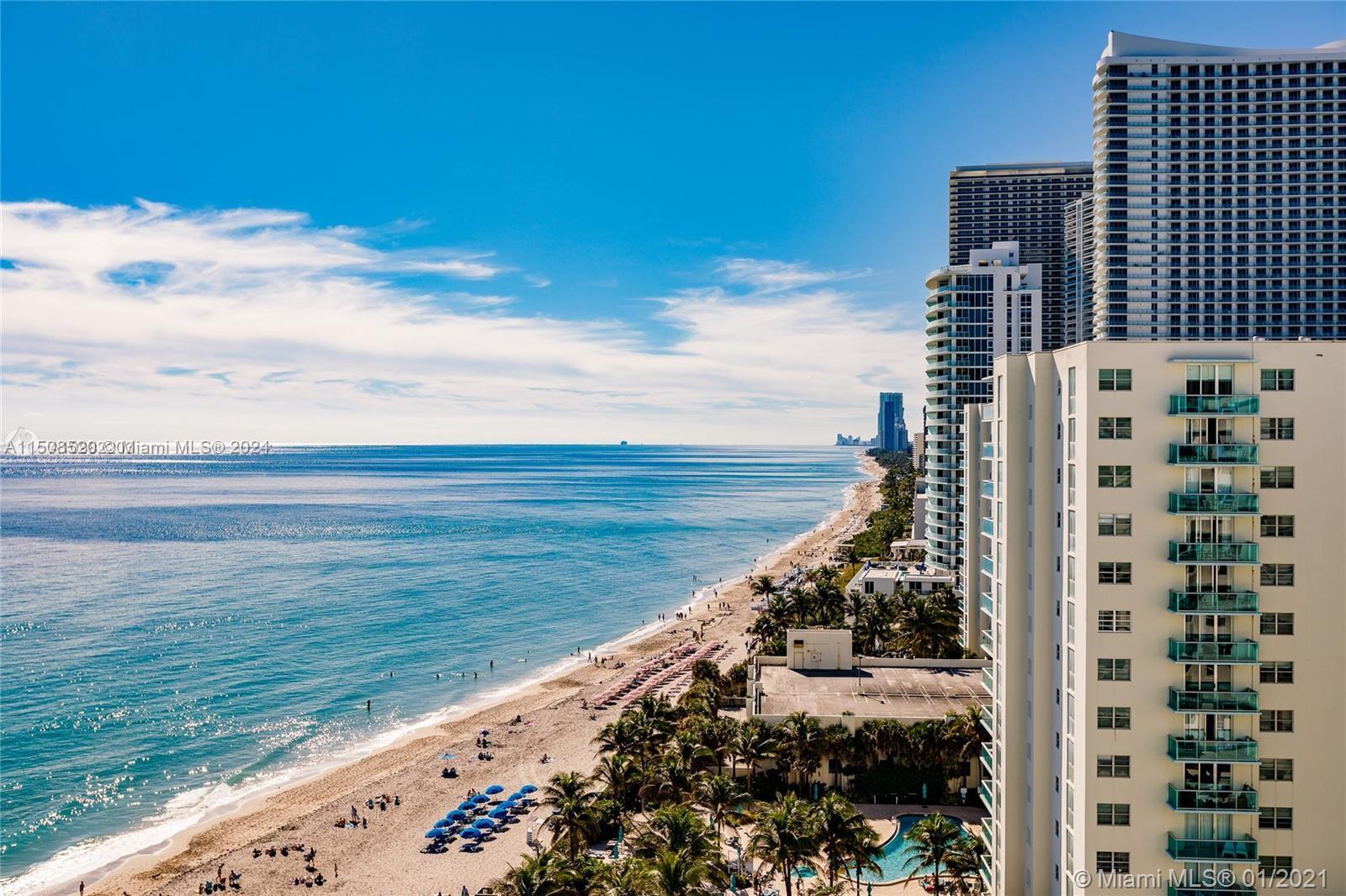 An aerial view shows a sandy beach with blue umbrellas alongside tall residential buildings — 3725 S Ocean Dr # 1504, Hollywood FL 33019, HOLLYWOOD, FL