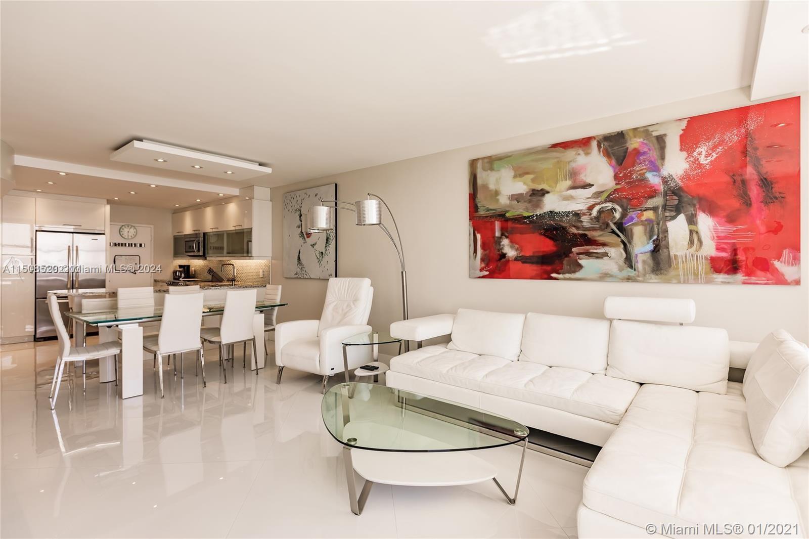 A modern open-concept living and dining area features white leather furniture and glossy tile floors — 3725 S Ocean Dr # 1504, Hollywood FL 33019, HOLLYWOOD, FL